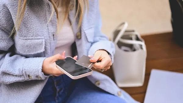 Frau hält eine NFC-Karte an ihr Smartphone