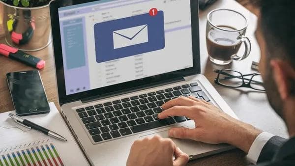 Profissional digitando em um notebook com um ícone de e-mail na tela.